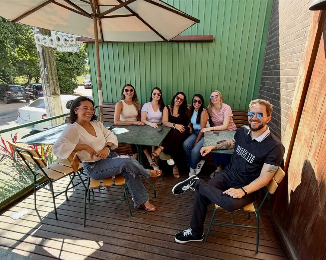 Grupo de pessoas sentadas à mesa na calçada da Padoca, sob guarda-sol, numa manhã de sol
